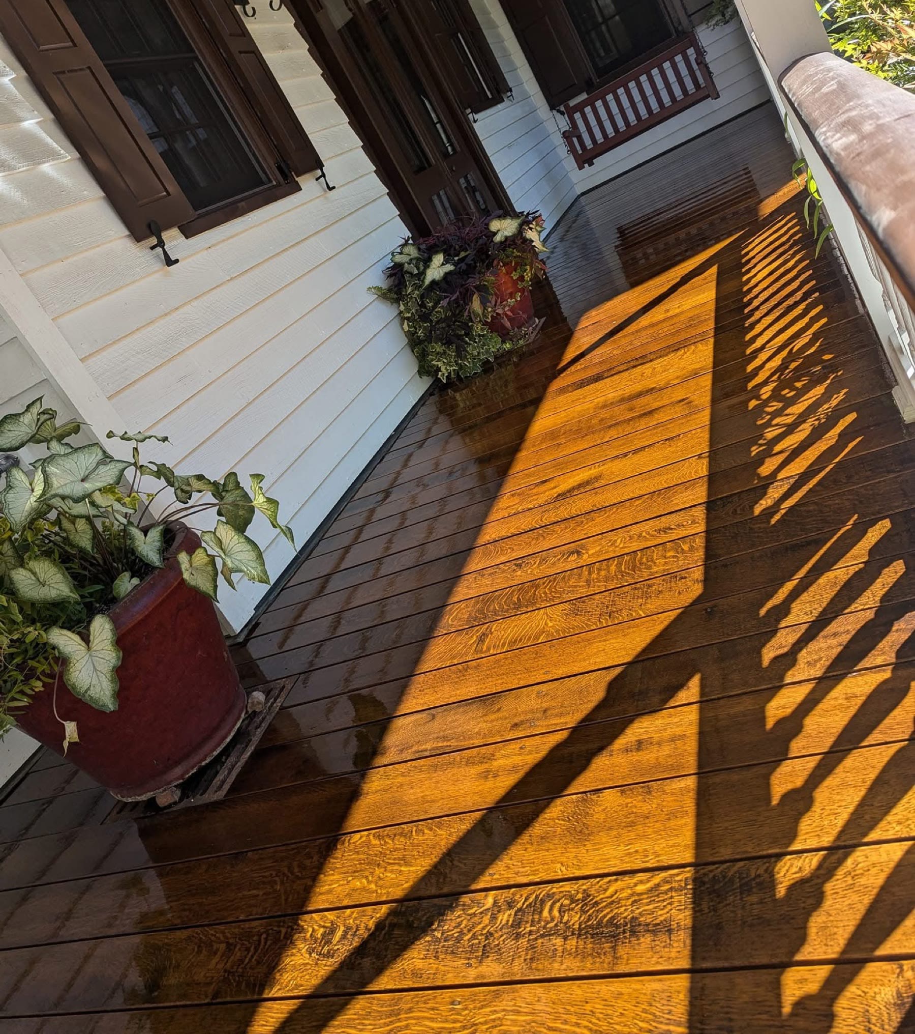 A front porch refinished by Flooring It — evening sun across fresh-stained boards